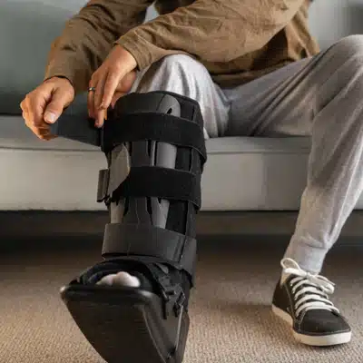 Patient secures an orthopedic walking boot for support after a leg or ankle injury recovery