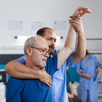 Therapist supports senior lifting arm in clinic, showing shoulder specialist dallas tx rehabilitation guidance session