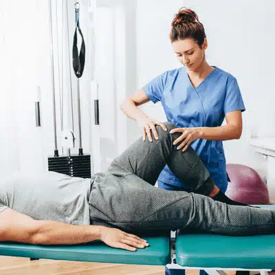 A clinician checks a patient’s knee movement during an exam with knee specialists for pain