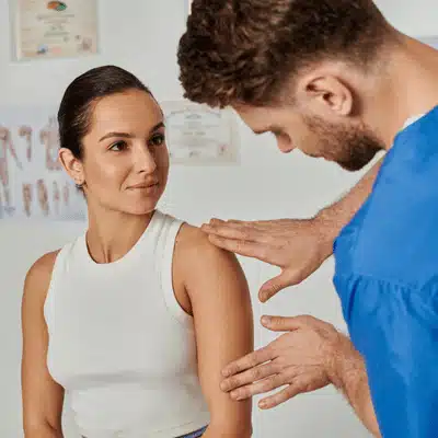 Clinician assesses patient’s shoulder in exam room, explaining dallas shoulder fracture evaluation and treatment options