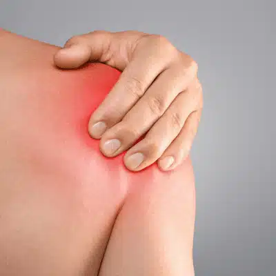 Closeup of red painful shoulder as person holds joint, possible rotator cuff tear dallas injury