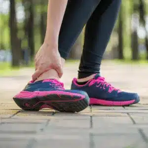Runner wearing pink sneakers stops due to sudden ankle pain when walking on pavement