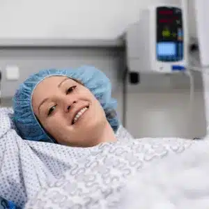 Smiling woman in hospital bed shows comfort after following shoulder surgery recovery tips closely