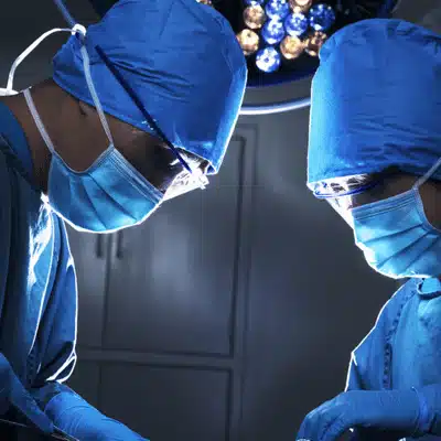 Surgeons in operating theatre focus under lights, performing precise shoulder procedure with sterile technique today