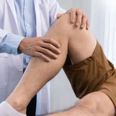 Doctor examines patient's bent knee for injury, discussing treatment options including possible meniscus transplant surgery