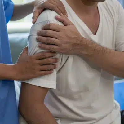 Clinician supports patient’s arm and shoulder during examination, assessing tenderness, stability, and pain response today