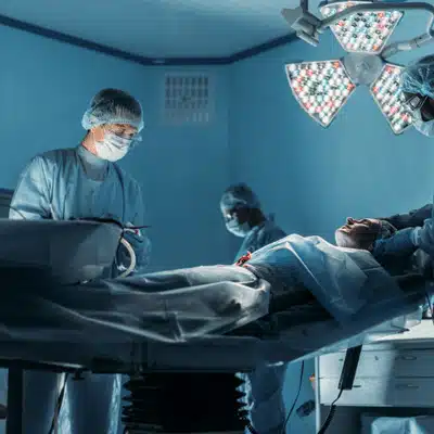 Surgeons perform procedure under bright operating lights, monitoring patient closely in sterile theater this morning
